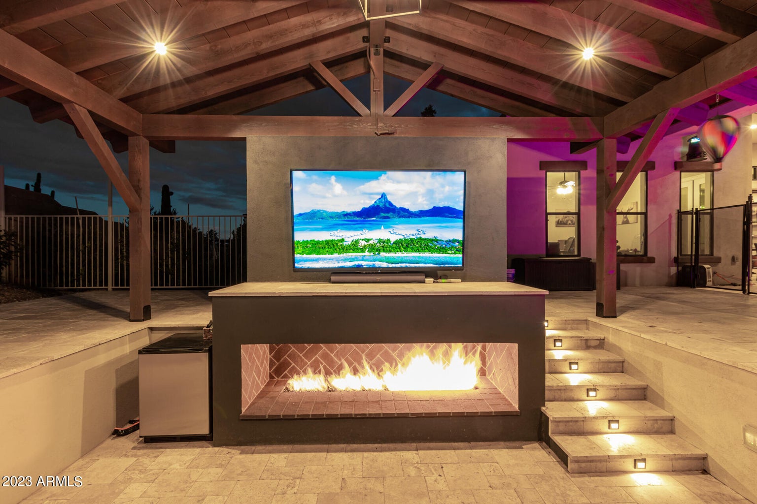 Luxury real estate with an outdoor fireplace showcasing a TV, developed by Denali Development Construction in the Greater Scottsdale area.